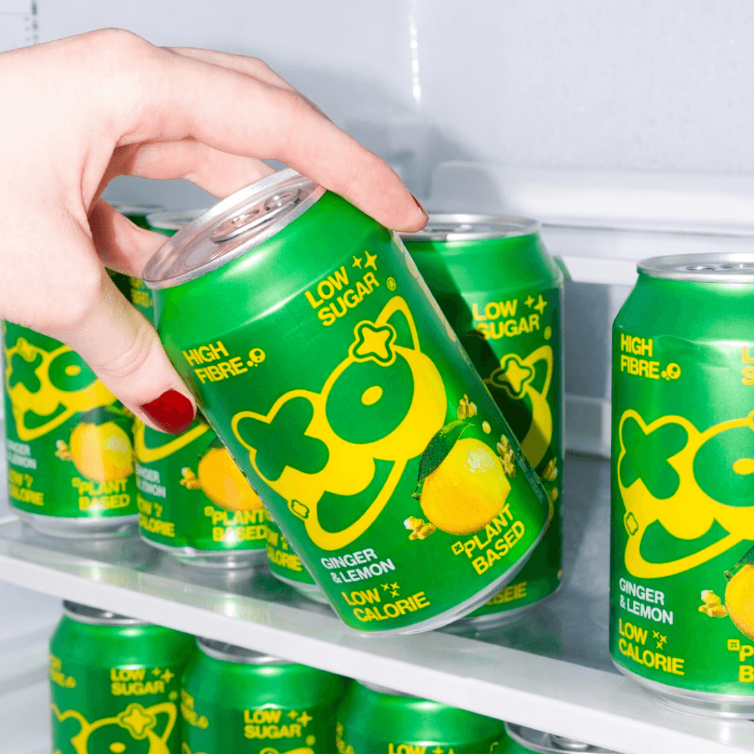 Refreshing XO Ginger Lemon Soda 12 pack displayed in a fridge, showcasing low sugar and plant-based ingredients.